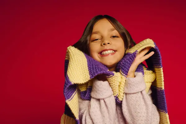 Smiling young girl showcases a vibrant knitted scarf amidst Christmas cheer in 2025. — Stock Photo