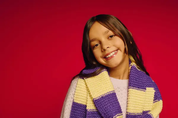 Little girl radiates happiness while wearing a colorful scarf, celebrating the magic of Christmas. — Photo de stock