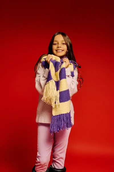 Ragazza sorridente in abbigliamento accogliente tiene una sciarpa calda, incarnando allegria di Natale nel 2025. — Foto stock