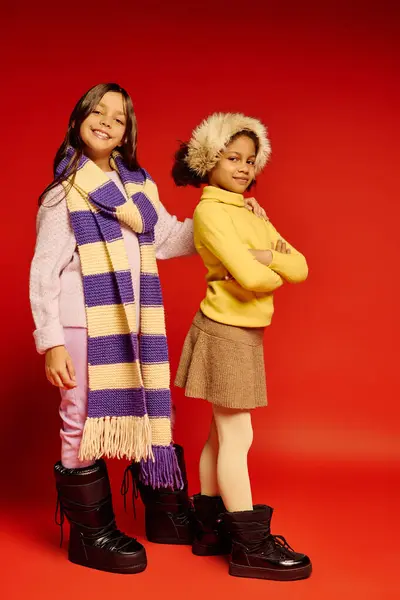 Two happy girls showcase their stylish holiday outfits, smiling joyfully in a warm setting. — Stock Photo