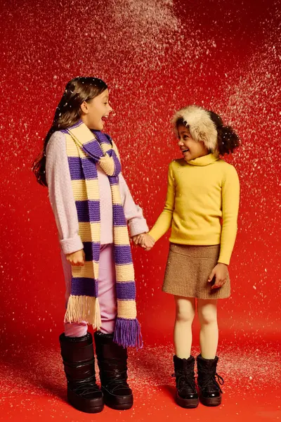 Two little girls holding hands, smiling brightly as snowflakes fall around them in festive cheer — Stock Photo