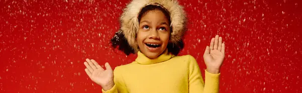 Girl joyfully celebrates the holidays in a bright yellow outfit amidst falling snow. — Stock Photo