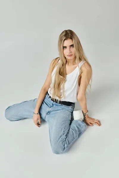 A stunning young woman with long blonde hair poses confidently in a serene studio. — Stock Photo