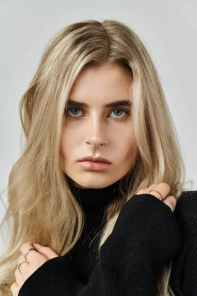 Long blonde hair frames the face of a young woman showcasing elegance in black attire. — Stock Photo
