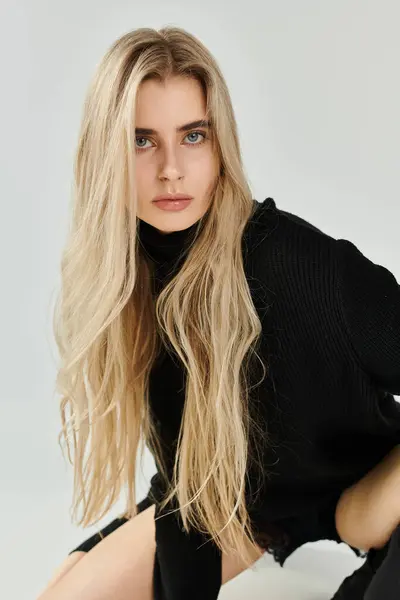 A striking young woman poses confidently in a chic black outfit, highlighting her beauty. — Stock Photo