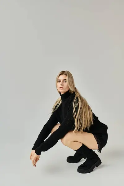 Uma jovem mulher com cabelo loiro longo posa graciosamente em uma roupa preta elegante. — Fotografia de Stock