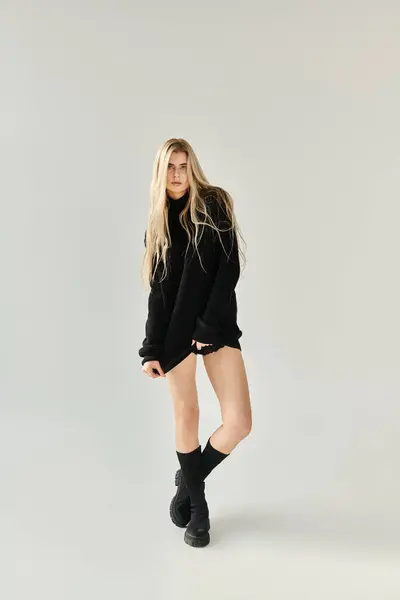 A stunning young woman with long blonde hair poses in elegant black attire, showcasing her beauty. — Stock Photo