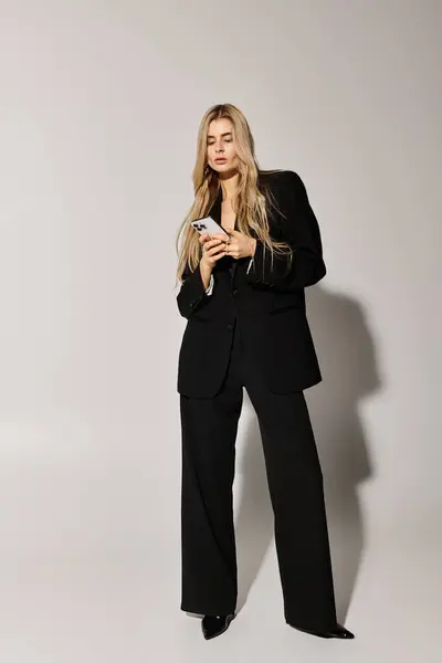 A stylish young woman in black attire flaunts her long blonde hair and fashion sense. — Stock Photo