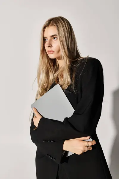 Une jeune femme en tenue noire élégante et de longs cheveux blonds pose gracieusement. — Photo de stock