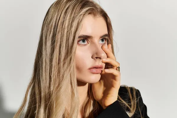 A young woman in black attire with long blonde hair poses elegantly. — Stock Photo