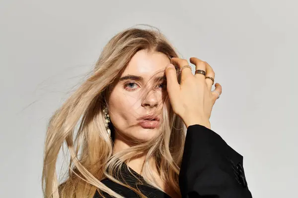 A beautiful young woman with long blonde hair poses gracefully in casual black attire. — Stock Photo
