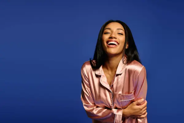 A beautiful young African American woman smiles joyfully while posing in silk pajamas. — Stock Photo