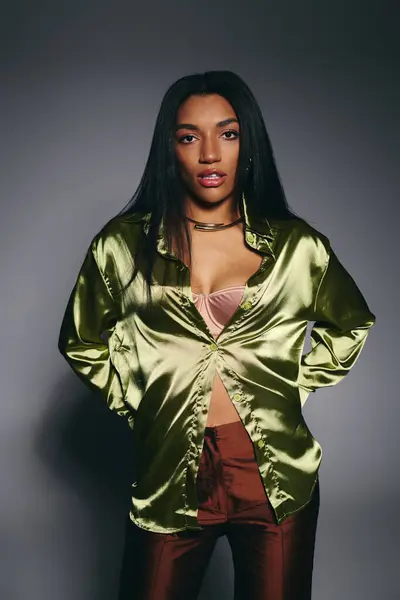 Joven mujer negra confiada posa en una elegante camisa de seda verde. - foto de stock