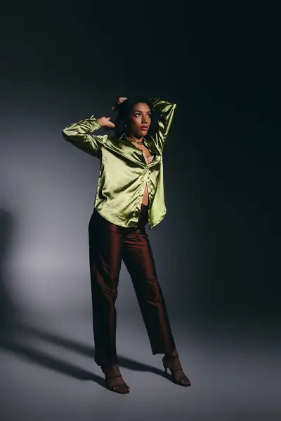 An attractive young African American woman showcases style in a green silk shirt while posing. — Stock Photo