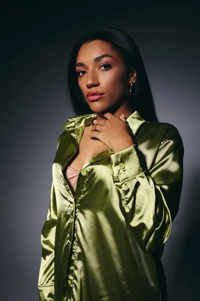 A graceful young African American woman poses in an elegant green satin blouse. — Stock Photo