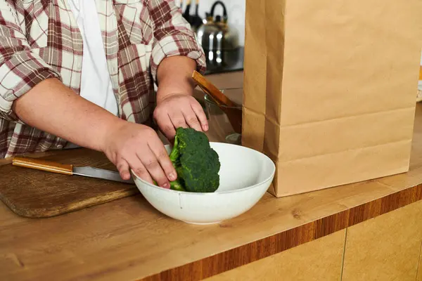 Young woman enjoys cooking as she prepares broccoli in a cozy kitchen setting. — Stock Photo