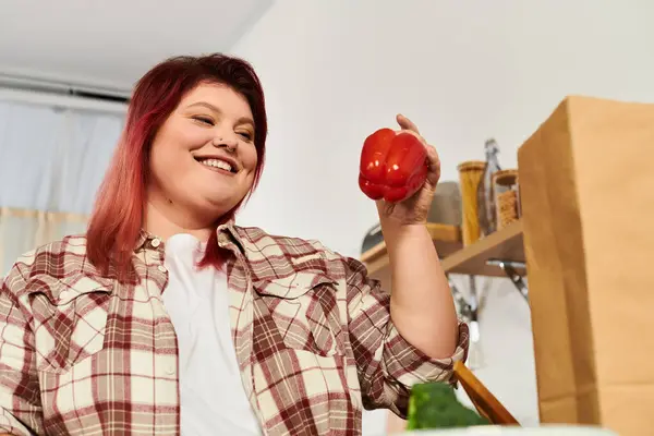 Smiling woman holds a red bell pepper, embracing her love for cooking healthy meals at home. — Stock Photo