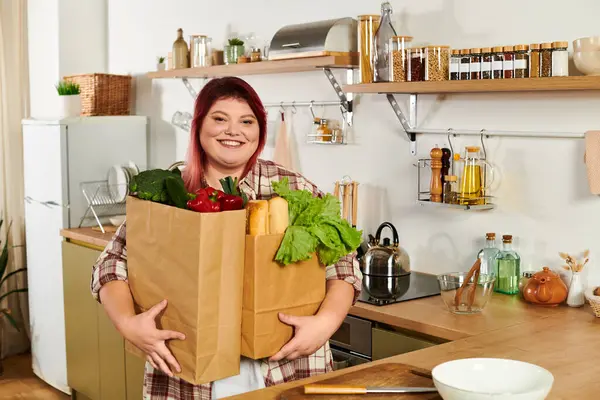Bright kitchen filled with warmth as a young plus size woman enjoys carrying fresh groceries. — Stock Photo
