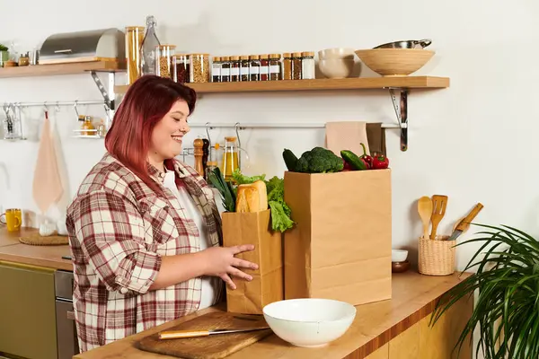 A cheerful young woman organizes fresh vegetables in her warm kitchen, enjoying the moment. — Stock Photo