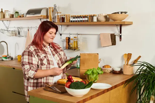 Young woman thoughtfully selects fresh vegetables while cooking in her bright kitchen space. — Stock Photo