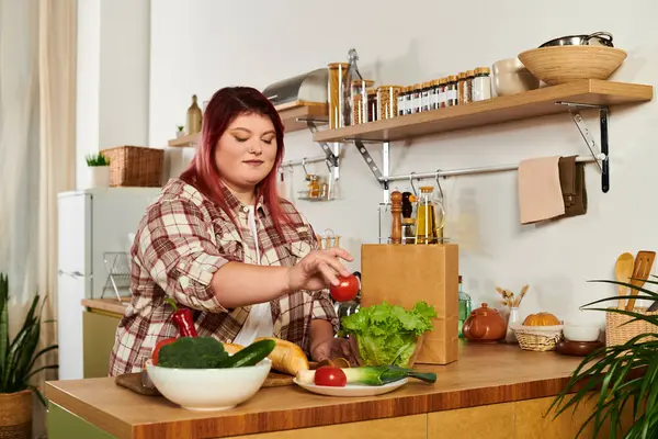 Bright kitchen setting features a young plus size woman chopping fresh vegetables on the counter. — Stock Photo