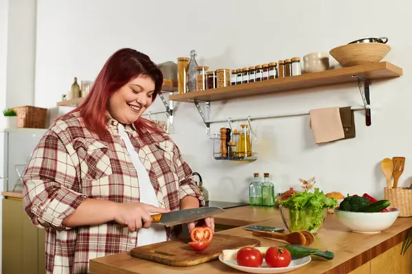Cheerful plus size woman slices tomatoes in her cozy kitchen. — Stock Photo