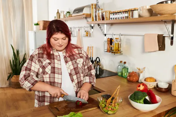 Plus size woman enjoys chopping vegetables for a colorful salad in a warm kitchen setting. — Stock Photo
