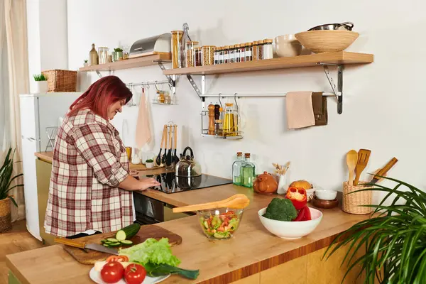 A young woman happily makes a colorful salad in her cozy, green filled kitchen. — Stock Photo