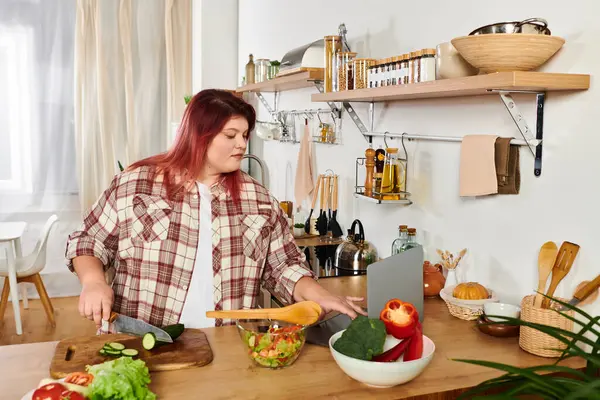 A young plus size woman skillfully chops veggies in a bright, cozy kitchen with greenery. — Stock Photo