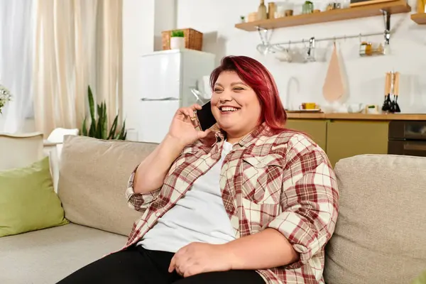 A beautiful young woman with plus size features smiles while talking on the phone in her home. — Stock Photo