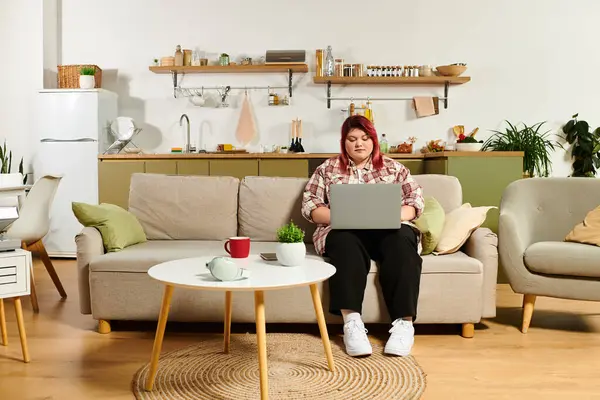 Plus size woman enjoys her time on a laptop in a stylish and inviting kitchen setting. — Stock Photo