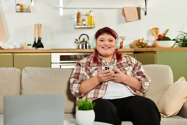 Jovem sorri em uma cozinha acolhedora, usando seu smartphone para se conectar com os outros. — Stock Photo