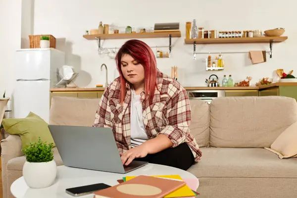 Young plus size woman focuses intently on her laptop while seated comfortably indoors. — Stock Photo