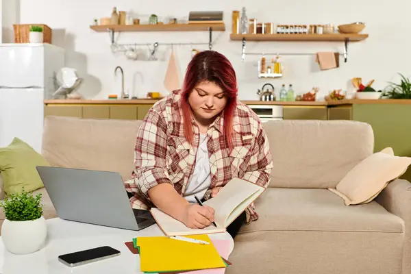 Focused plus size woman writes notes and ideas while seated comfortably in her cozy living space. — Stock Photo
