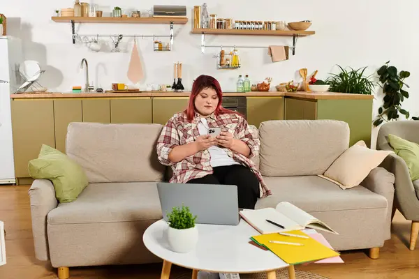 Young woman relaxes at home, focused on her phone while surrounded by creative materials. — Stock Photo