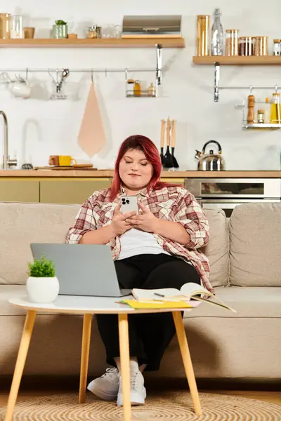 A young plus size woman relaxes on a couch, engaged with her smartphone in cozy decor. — Stock Photo