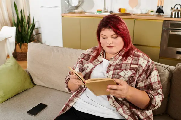 Женщина plus size погружается в чтение книги, расслабляясь в теплой и уютной домашней обстановке. — стоковое фото