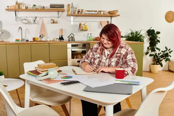 Joyful plus size woman engages in creative tasks at a stylish kitchen table filled with notes. — Stock Photo