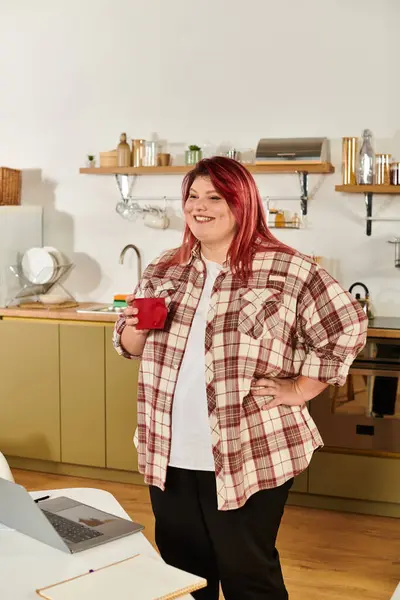 Young plus size woman smiles warmly while holding a mug in her modern kitchen space — Stock Photo
