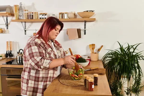 Plus size woman prepares a colorful salad in her stylish kitchen while enjoying the process. — Stock Photo