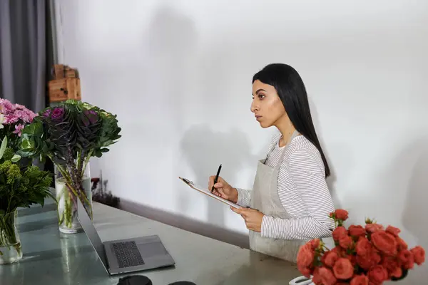 Una fiorista bruna organizza abilmente fioriture vivaci nel suo negozio di fiori. — Foto stock