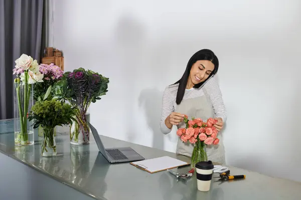 Brunette florist arranges vibrant flowers while managing her small business tasks. — Stock Photo