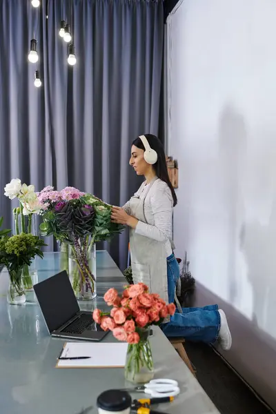A creative florist organizes vibrant blooms while managing her small business tasks. — Stock Photo