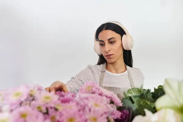 Una florista dedicada organiza meticulosamente floraciones coloridas mientras disfruta de su oficio en la tienda.. - foto de stock