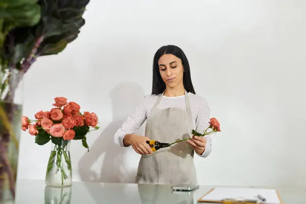 Bella bruna fiorista organizza abilmente rose mentre gestisce la sua piccola impresa. — Foto stock