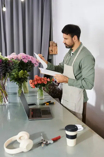 Florist reviews arrangements while preparing blooms in his charming shop filled with flora. — Stock Photo