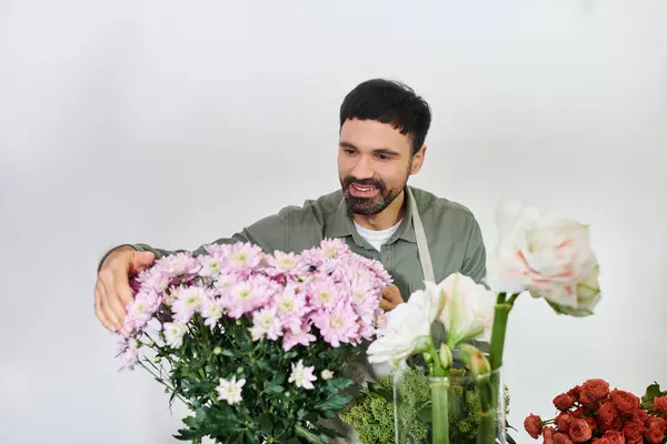 Um homem barbudo artisticamente arranja flores deslumbrantes em sua loja, mostrando seu amor pela floricultura. — Fotografia de Stock