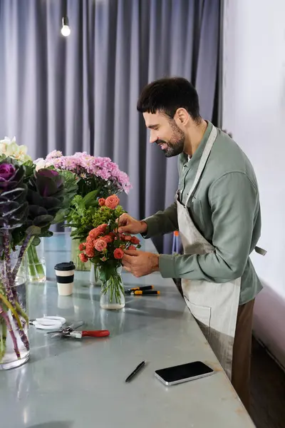 A skilled florist meticulously arranges a bouquet in a bright shop filled with blooms. — Stock Photo