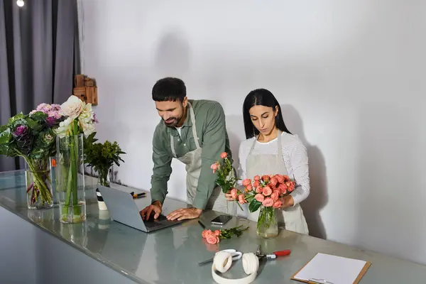 Una pareja crea impresionantes arreglos florales mientras dirigen su pequeño negocio juntos. - foto de stock