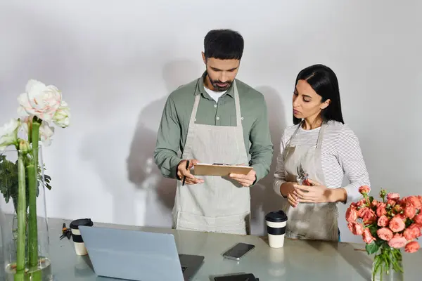 Dos floristas apasionados trabajan juntos en su pequeña empresa, elaborando diseños florales únicos. - foto de stock